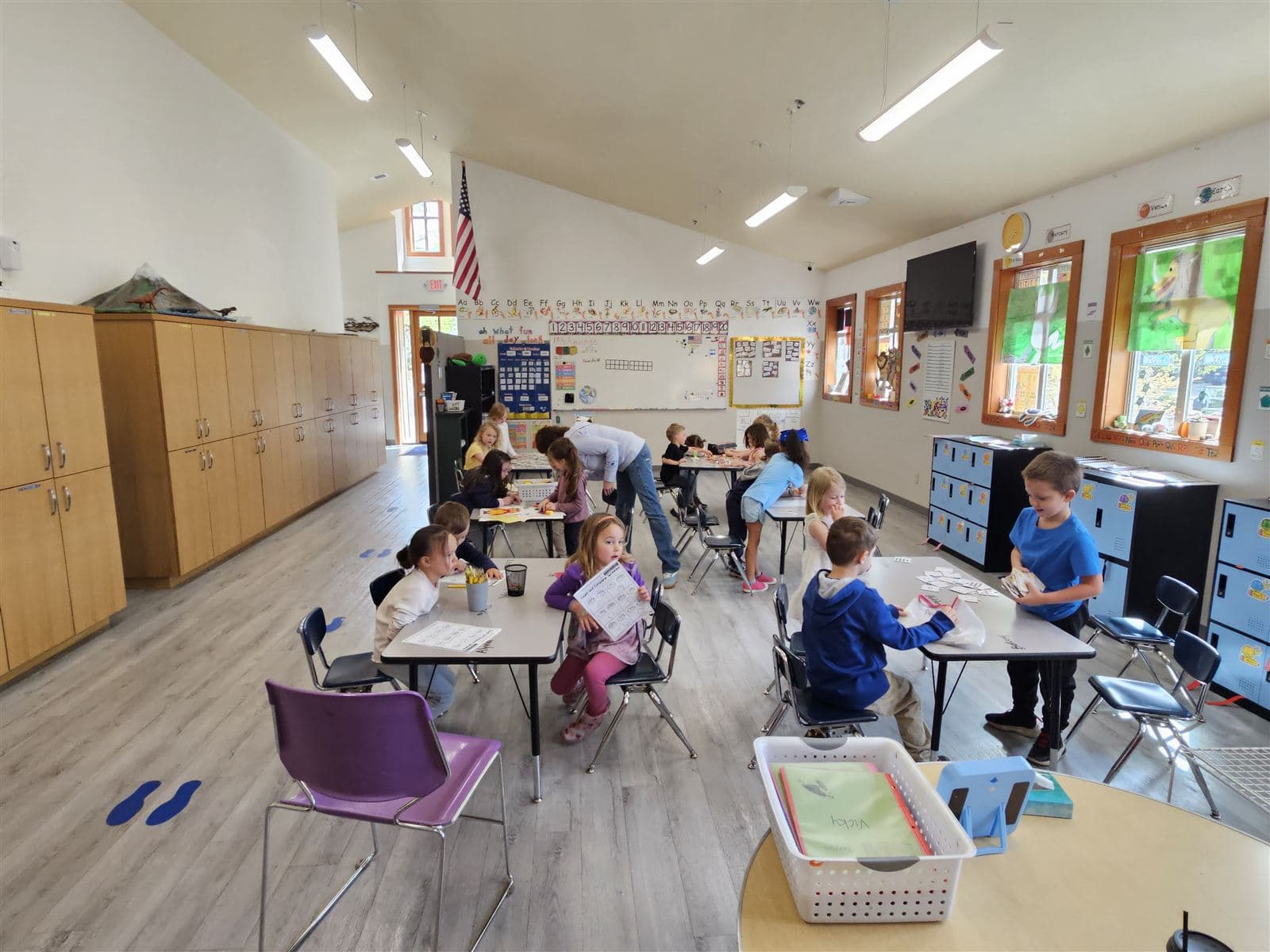 A teacher helping a student one-on-one in the bright classroom