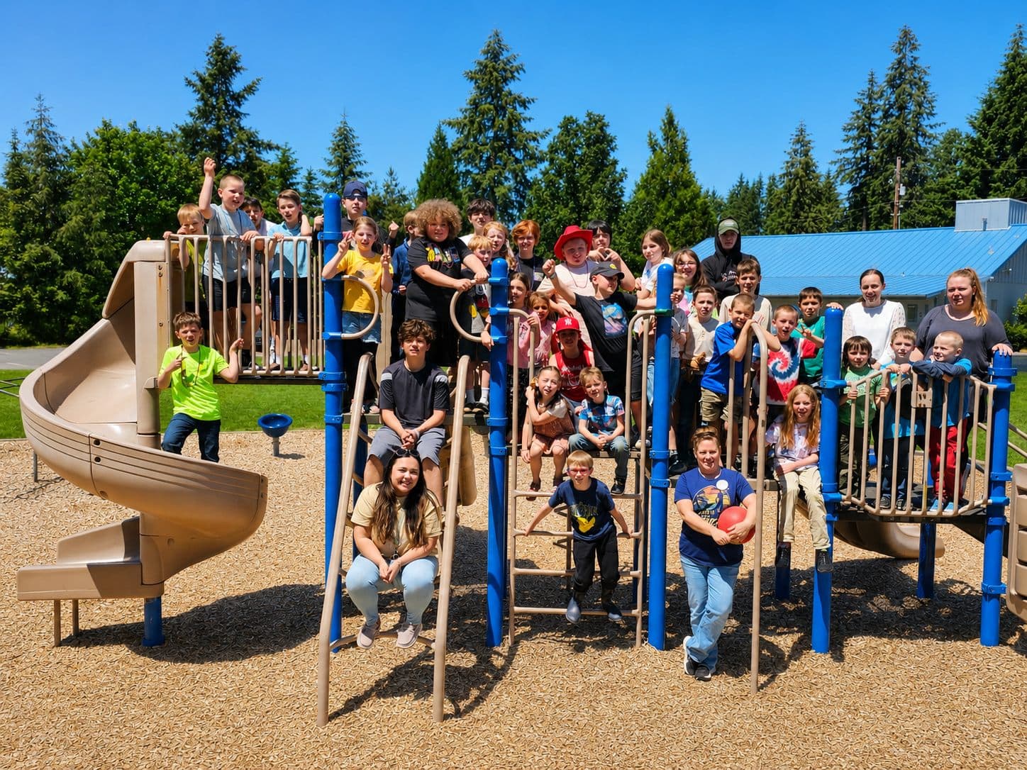 The whole school and their teachers on the playground climber on a bright blue-sky day