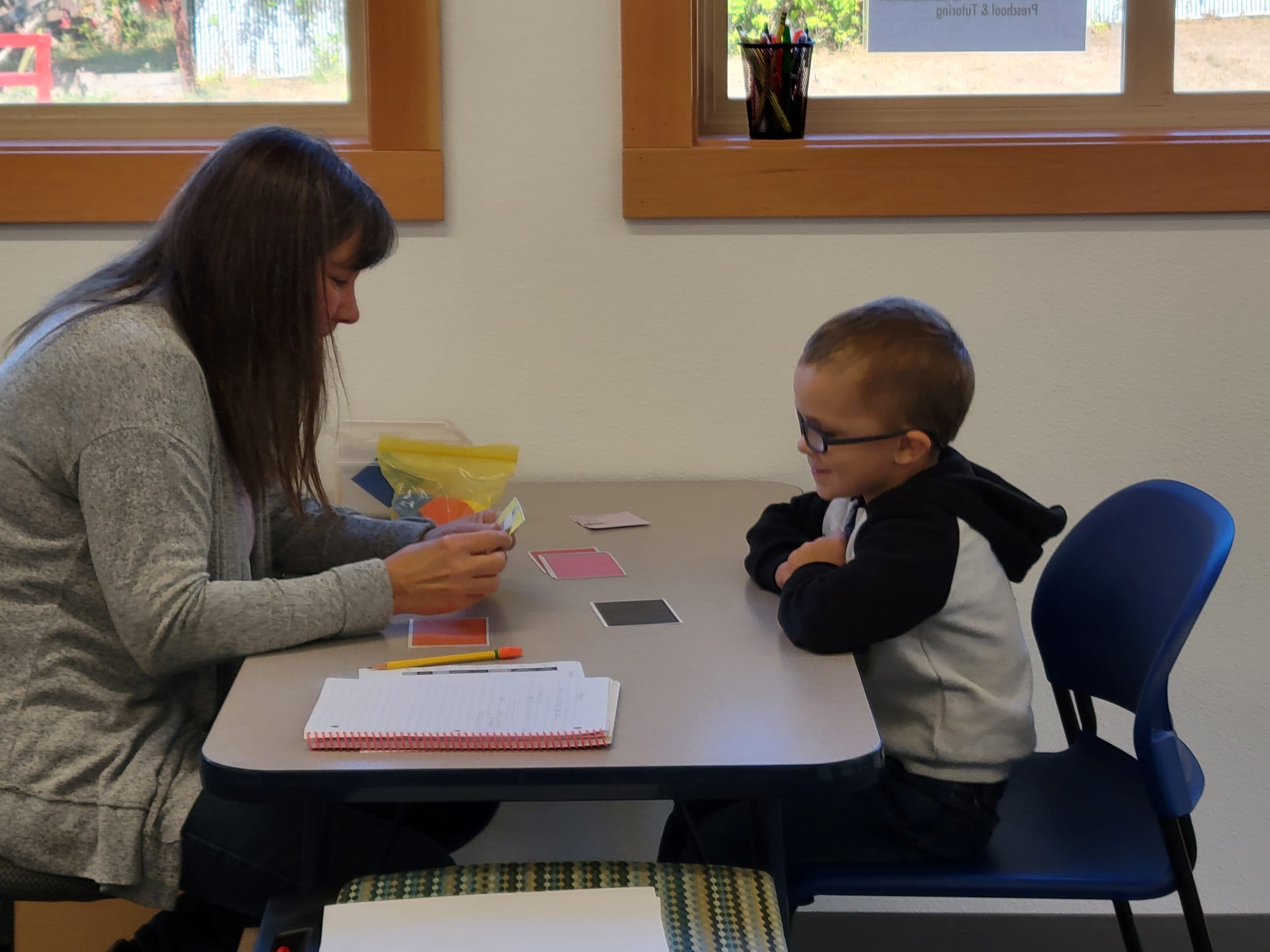 A tutor working one-on-one with a student at a small table by the window